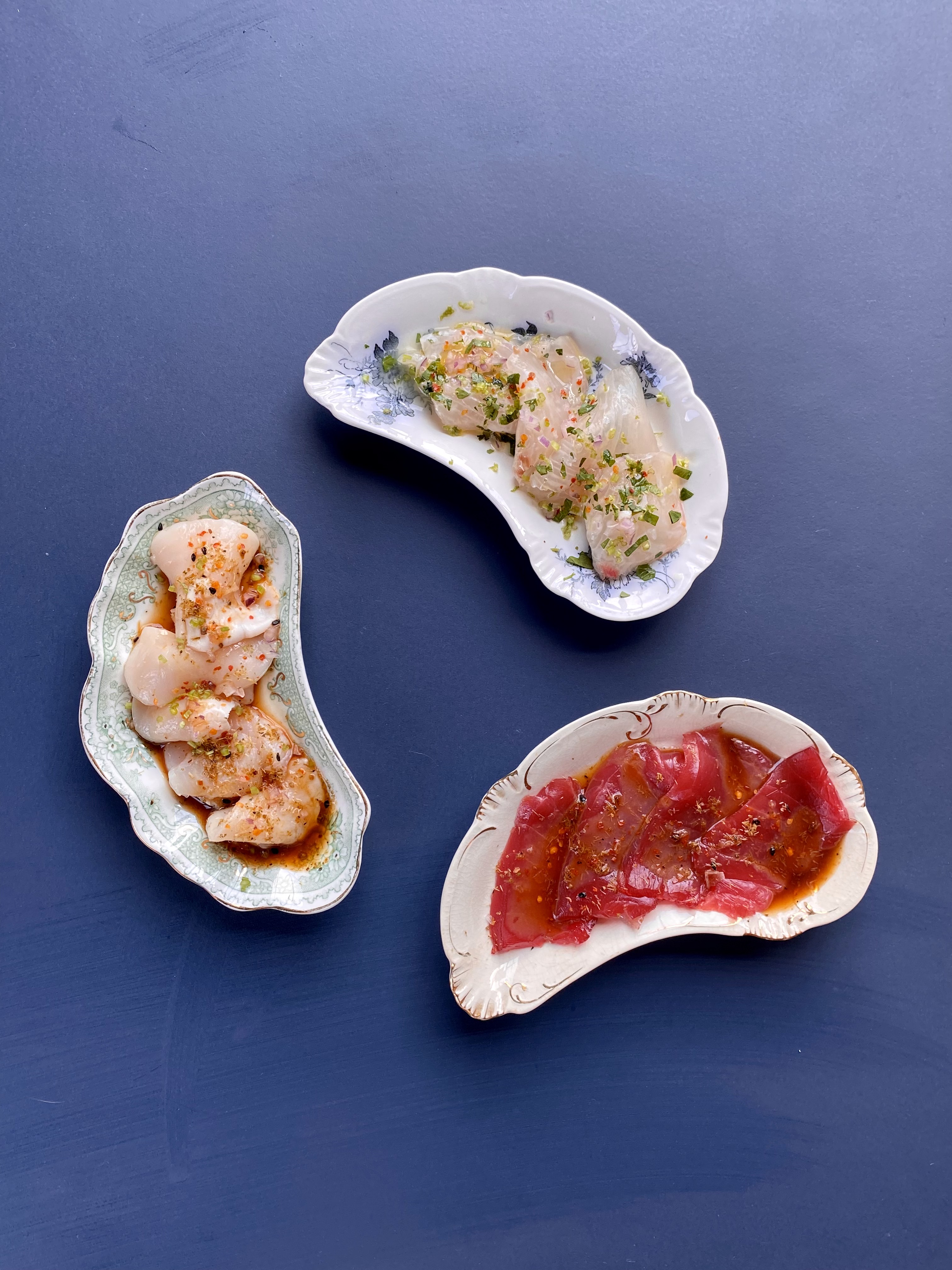 Three crudo dishes on vintage porcelain plates