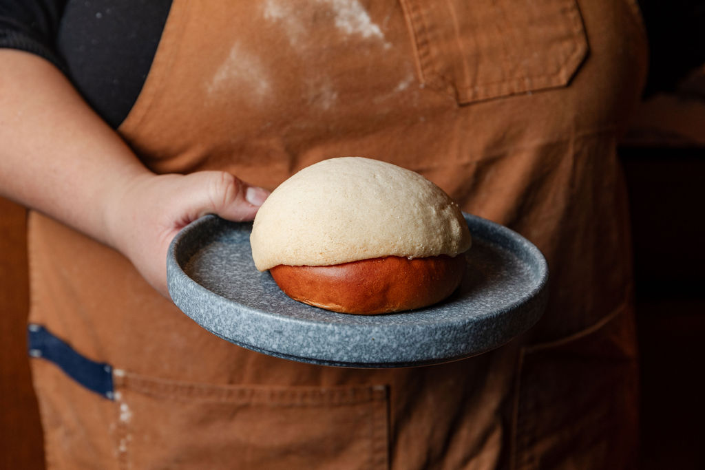 Baker holding a concha on a stone plate